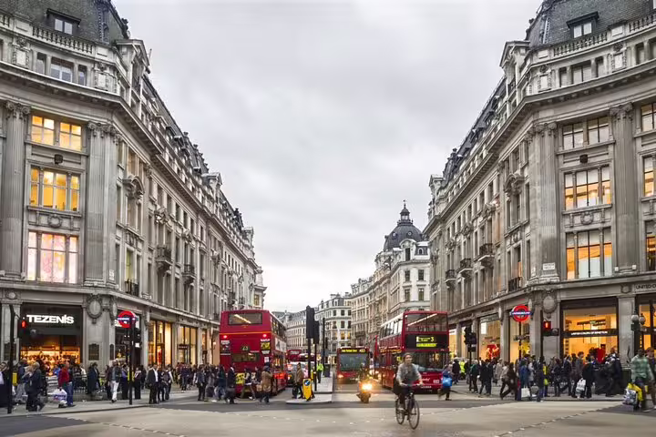 Busy Oxford Street London with red double-decker buses, historic buildings and crowds of pedestrians
