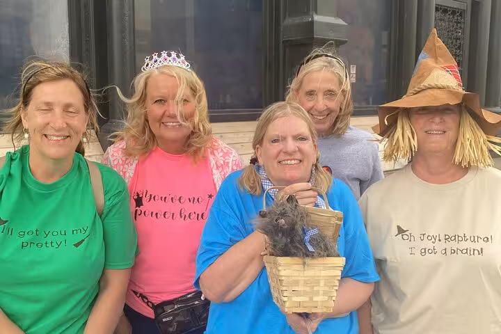 Oz Wicked Glitch Experience Omaha participants in Wizard of Oz costumes including scarecrow and Glinda smiling outdoors