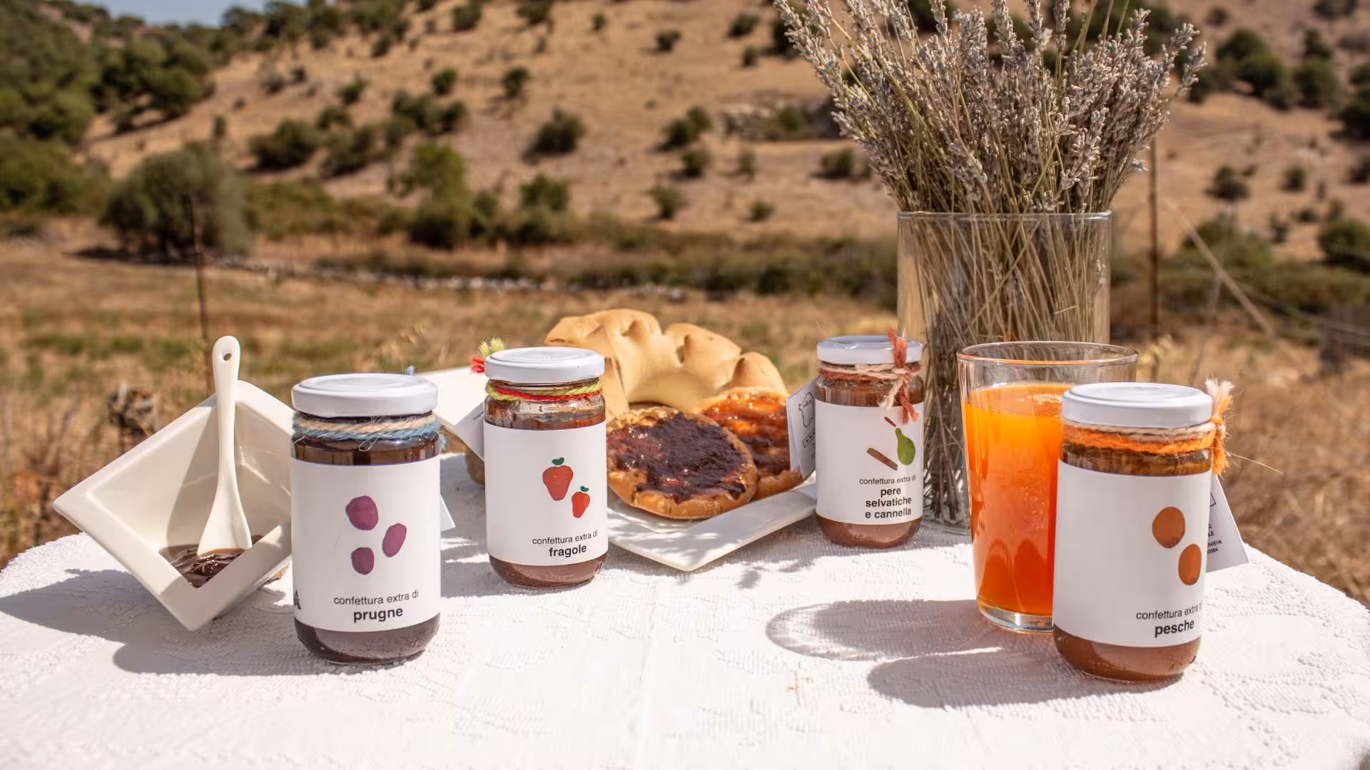 Assorted jam jars, pastries, and juice set on a table against Tula’s picturesque landscape for a delightful tasting.