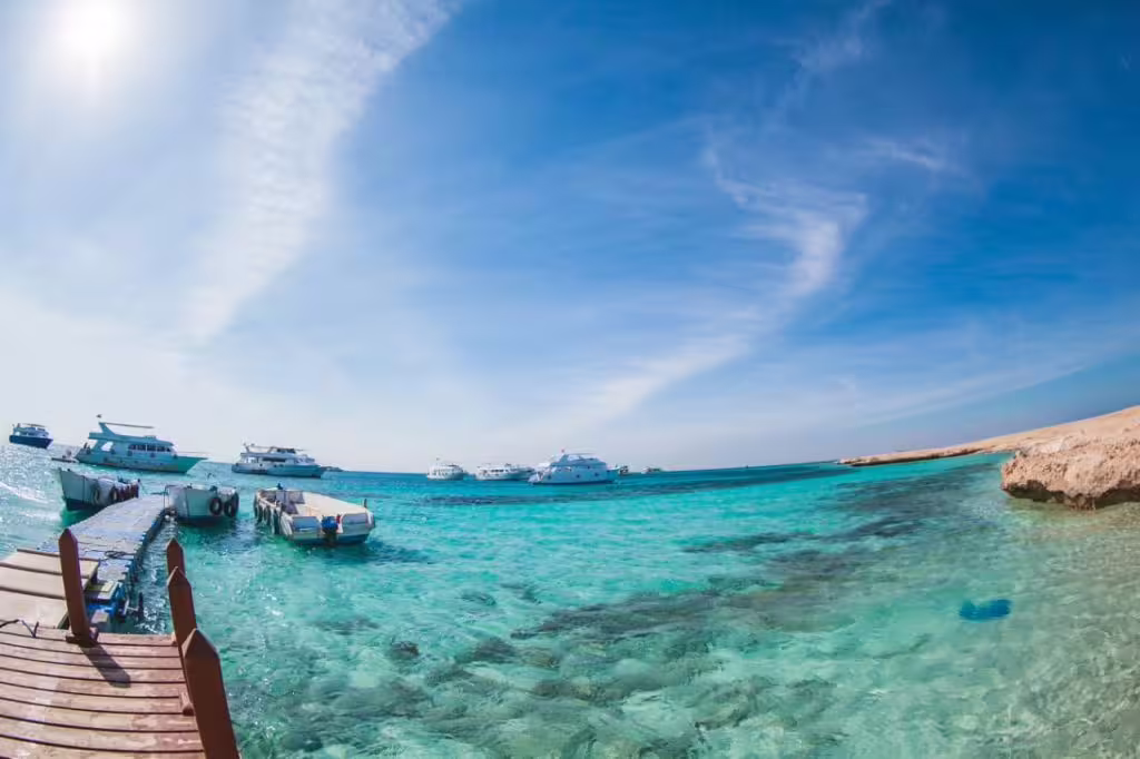 Crystal-clear turquoise lagoon with boats and jetty on Paradise Island day trip, ideal for snorkeling and swimming