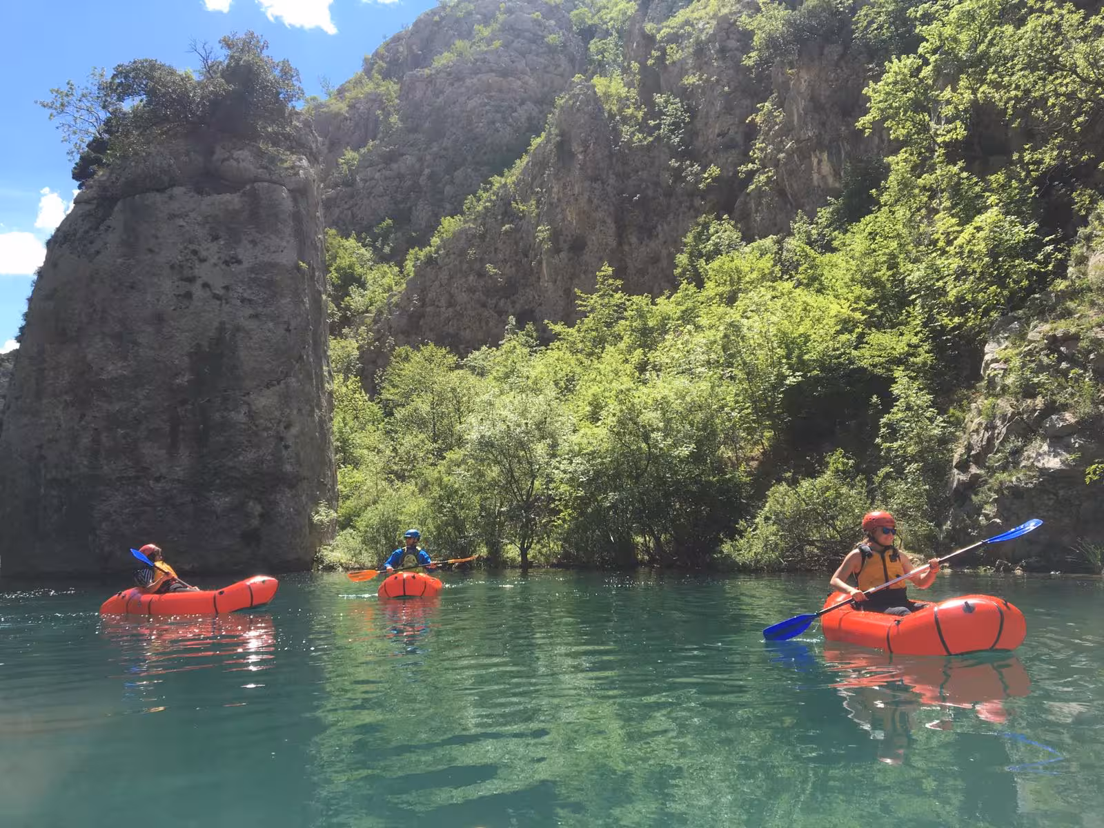 Adventurers packrafting through scenic Zrmanja River canyon under clear skies, perfect for nature lovers.
