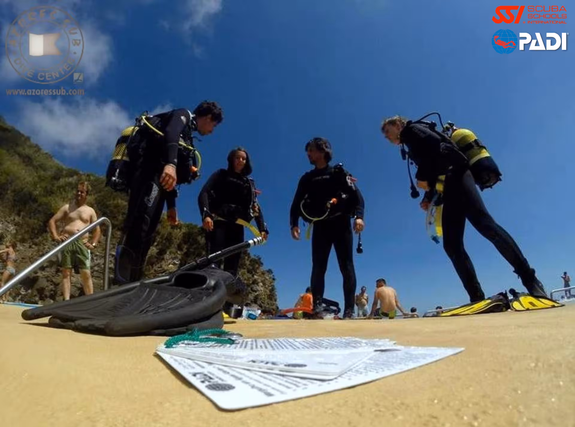 PADI Divemaster trainees gearing up on São Miguel shore dive, Azores, with fins and briefing paperwork in foreground