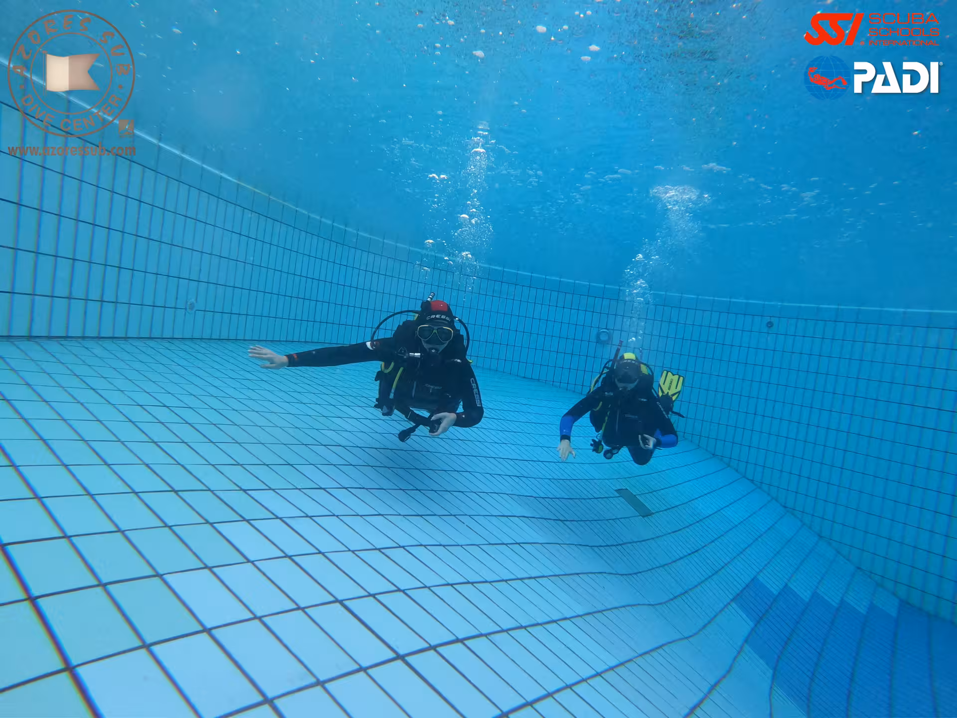 PADI Perfect Buoyancy pool session with two scuba divers hovering neutrally above tiled floor, controlled trim