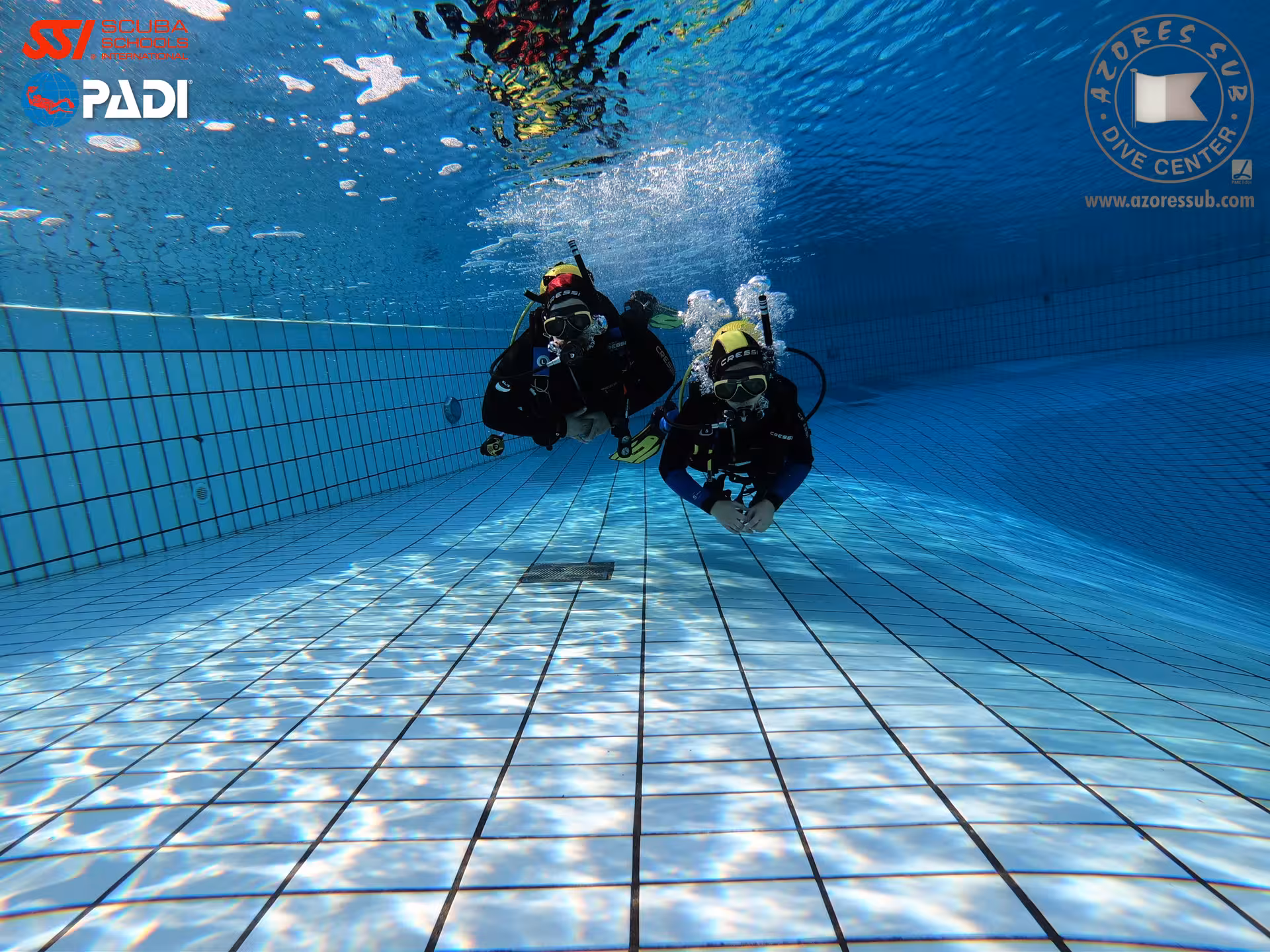 Two scuba divers practice perfect buoyancy skills in a pool during a PADI buoyancy specialty session