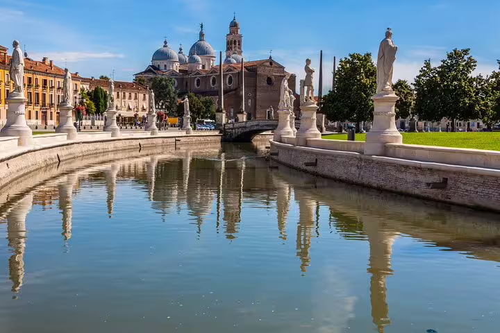 Prato della Valle canal and statues in Padua with domes of the Basilica of Santa Giustina on a personalized walking tour route