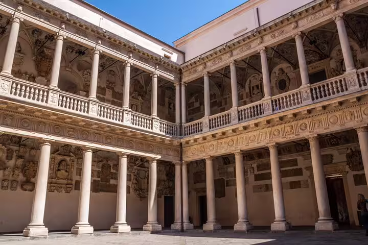 Historic courtyard of Palazzo Bo in Padua with ornate columns, balconies, and Renaissance frescoed walls