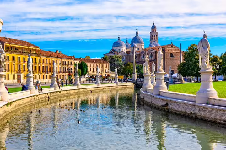 Prato della Valle canal with white statues and Santa Giustina Basilica domes in Padua, Italy