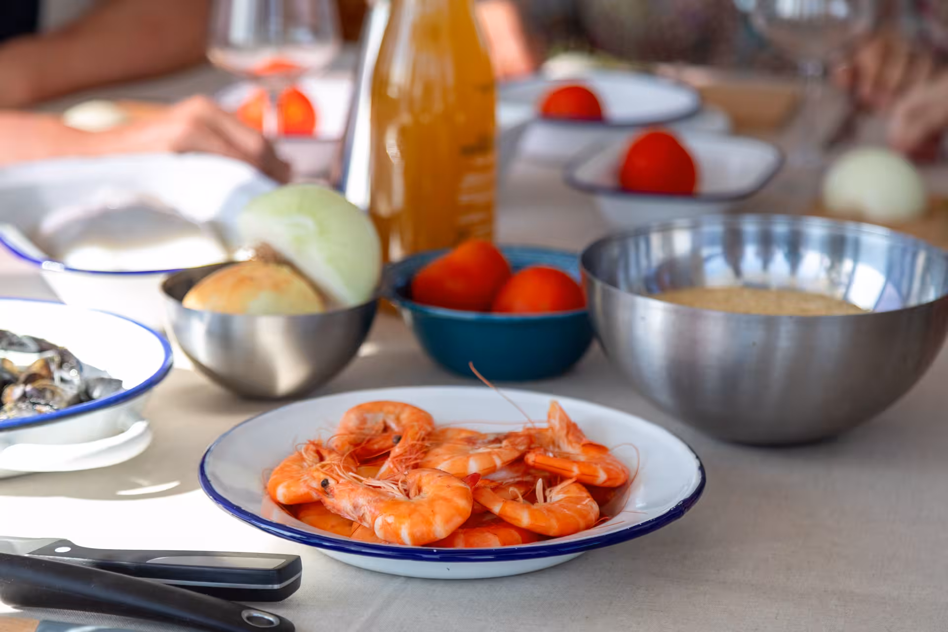 Paella Masterclass ingredients on table with prawns, rice, tomatoes, onion and olive oil for Spanish cooking