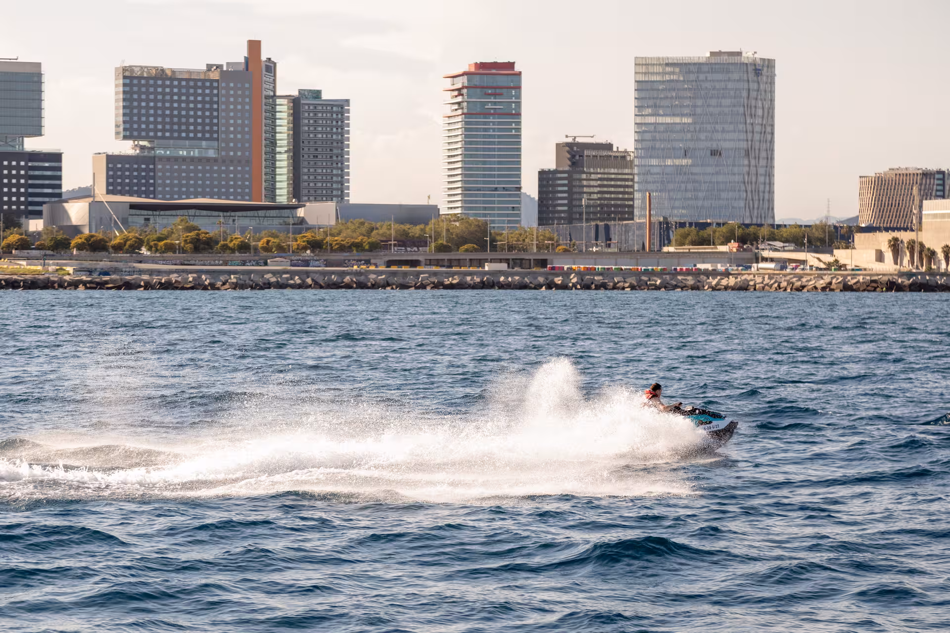 Speedboat racing along Barcelona coastline, exciting add-on for Paella Masterclass cooking experience in Spain