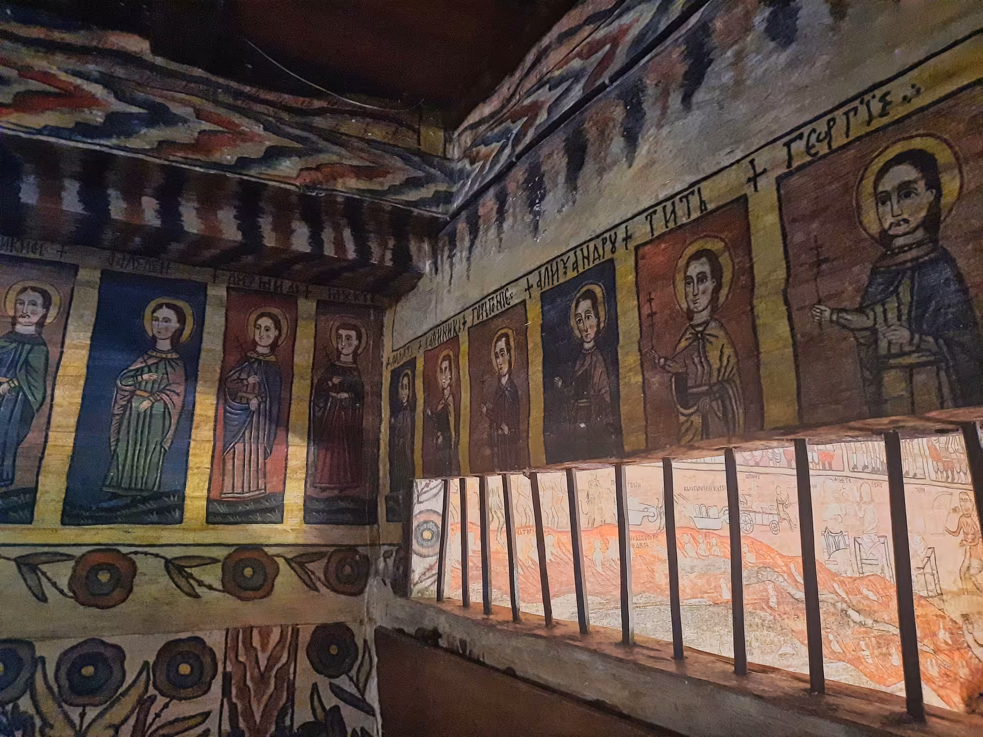 Colorful interior frescoes depicting Orthodox saints and scenes covering walls of a traditional painted wooden church visited on Maramures Bucovina tour from Cluj