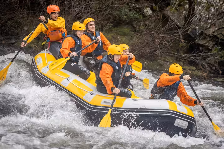 Group rafting the Paiva River from Porto, Portugal, paddling a yellow raft through fast whitewater rapids