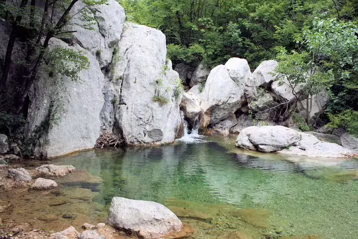 Clear emerald pool and small waterfall among limestone boulders in Paklenica National Park, Croatia