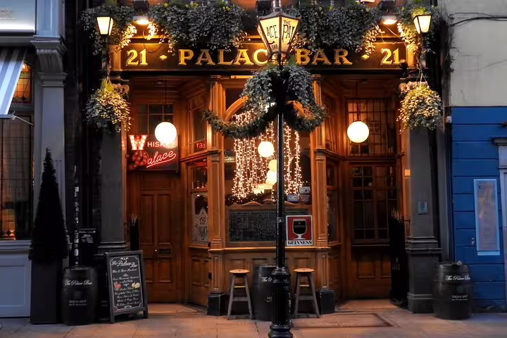 Palace Bar Dublin pub exterior with warm lights, ivy garlands, and Guinness sign at 21 Fleet Street