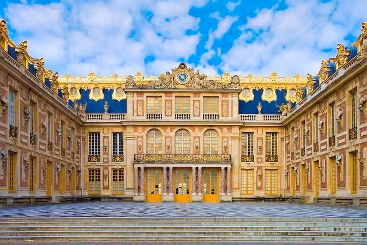 Grand courtyard facade of the Palace of Versailles with golden doors and ornate Baroque architecture