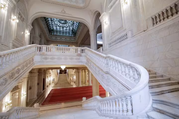 Opulent marble staircase with intricate carvings inside Bucharest's Palace of Parliament.