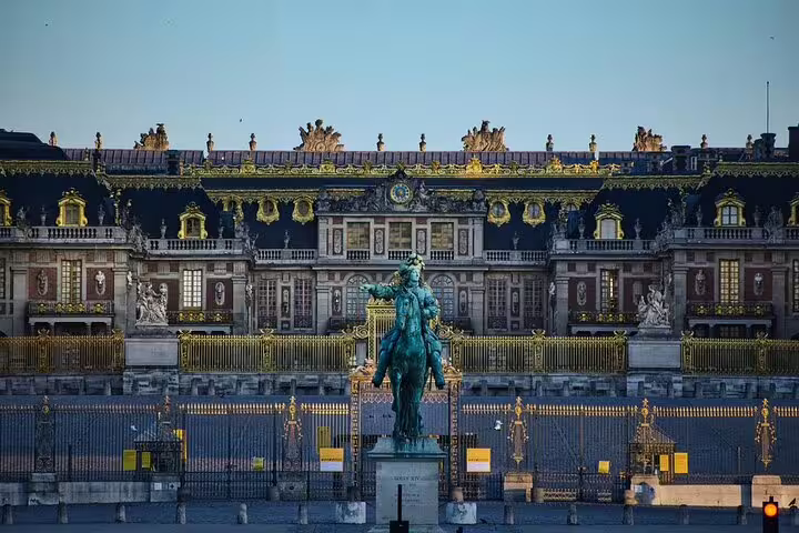 Palace of Versailles facade with Louis XIV equestrian statue and ornate golden gates