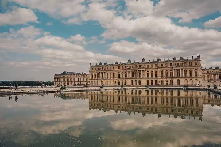 Palace of Versailles reflecting in the ornamental pool under a partly cloudy sky, France