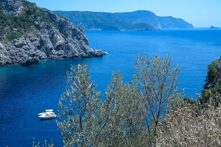 Palaiokastritsa bay viewpoint in Corfu with turquoise Ionian Sea, cliffs and boat on small group tour