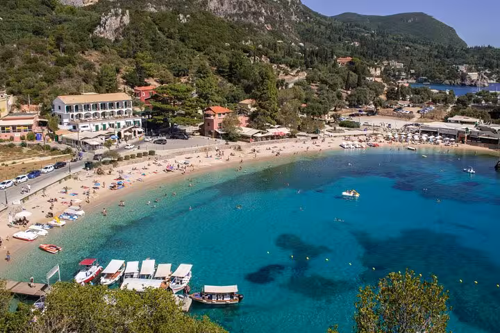 Aerial view of Palaiokastritsa beach, Corfu with clear blue water, boats and seaside village on 4-hour tour