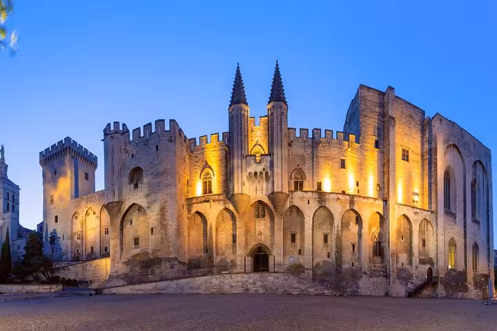 Palais des Papes illuminated at dusk in Avignon, France, showing Gothic medieval architecture