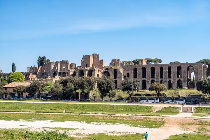 View of the ancient Palatine Hill ruins under a clear blue sky, part of Rome's historical tour with tickets included.