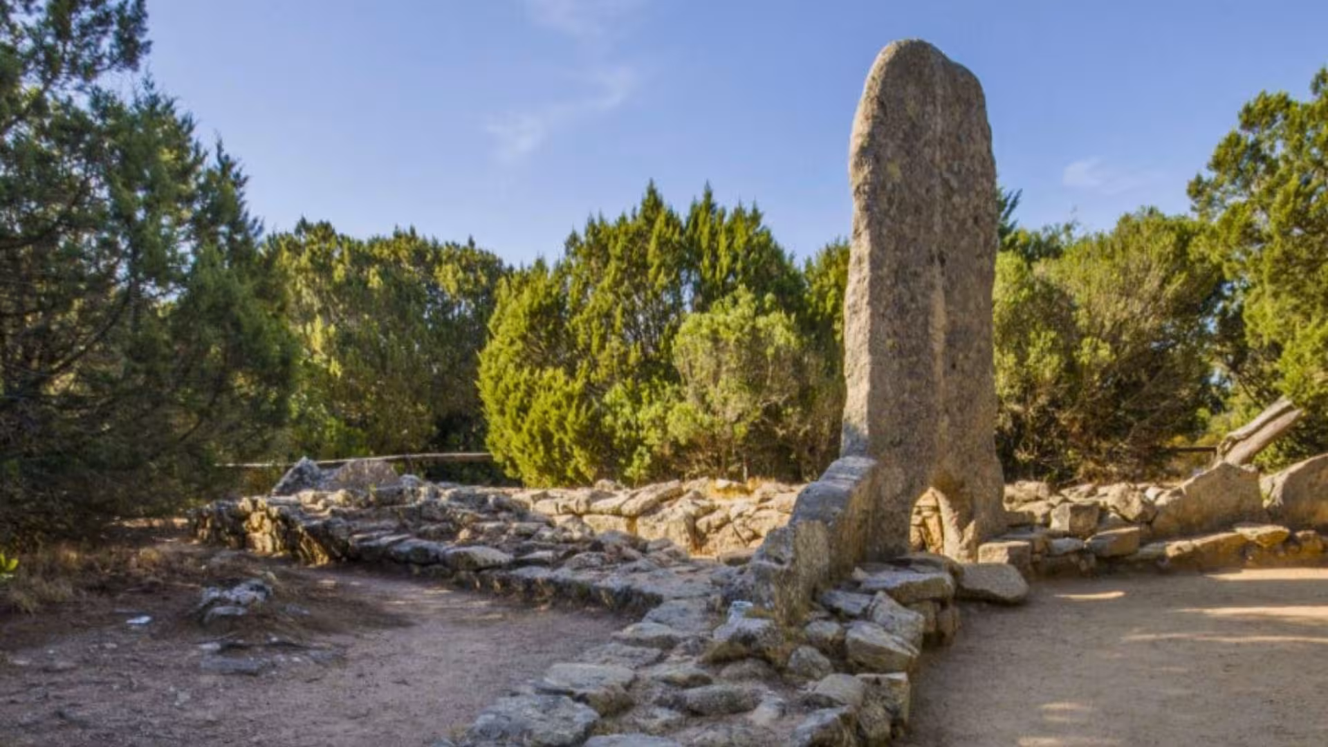 Ancient stone structure surrounded by lush greenery in the archaeological site of Palau, Sardinia.