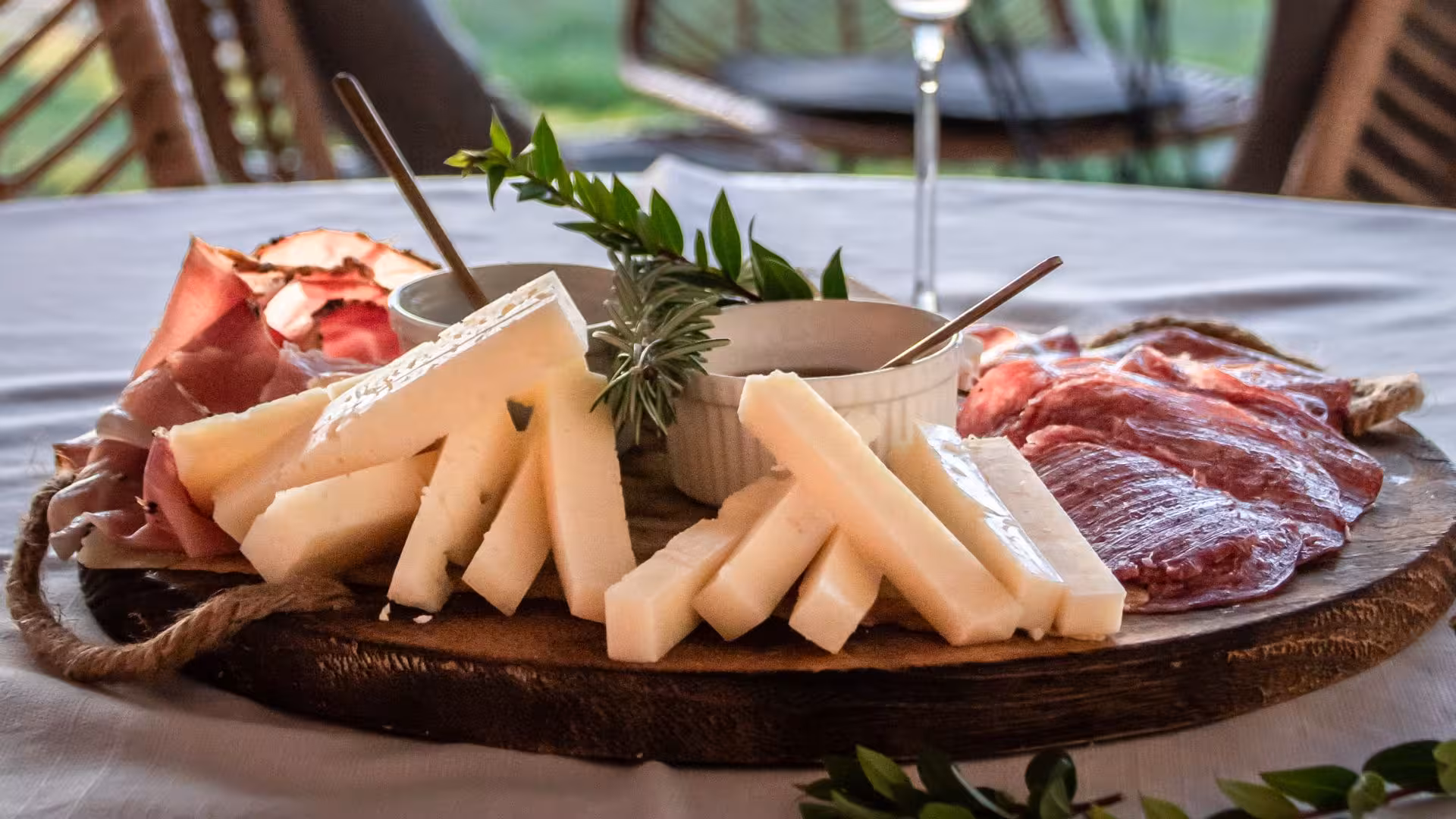 Cheese and cured meat platter with herbs at a Gallura winery tasting in Palau.