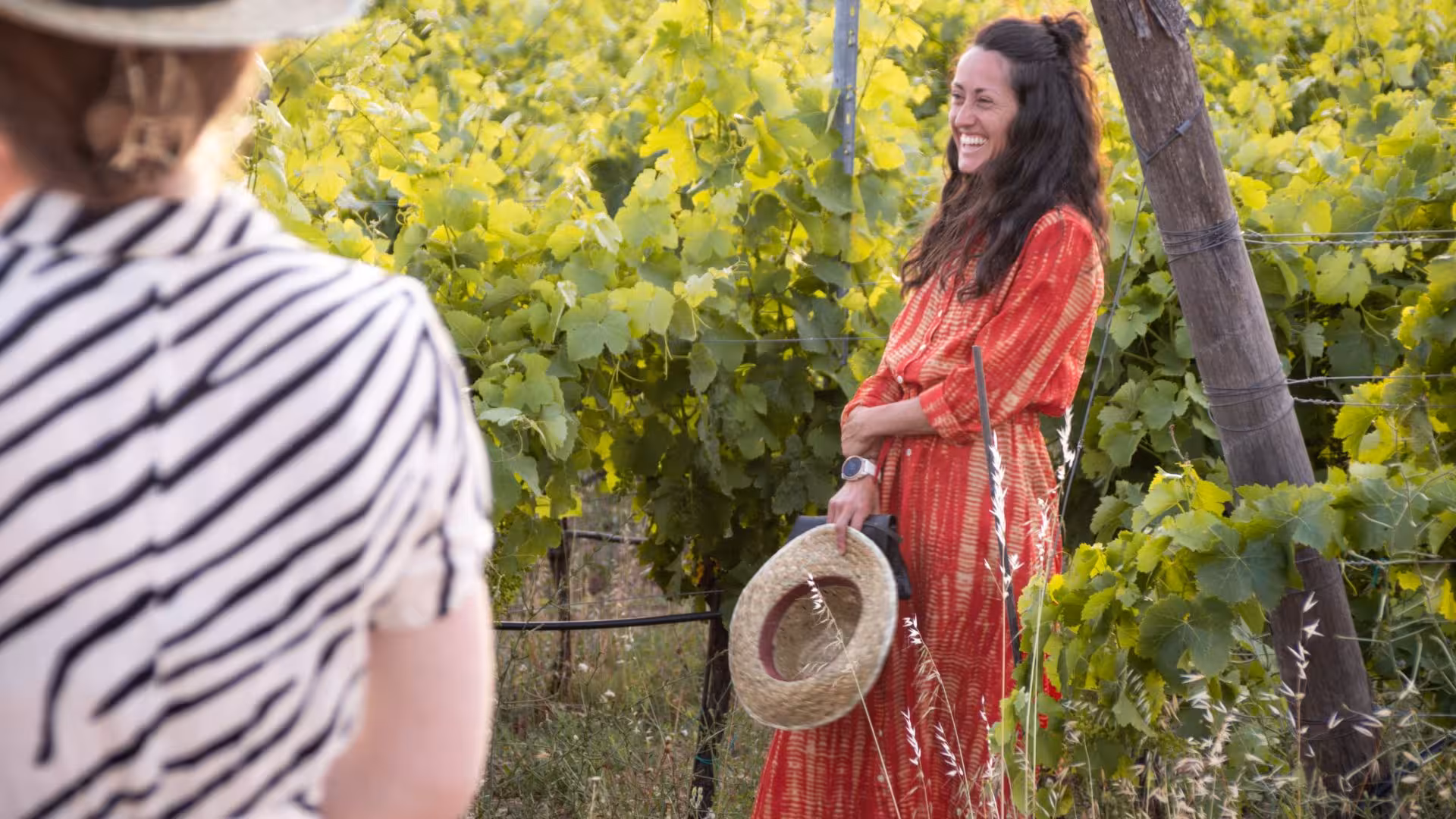 Smiling visitor in a red dress enjoys a sunny vineyard tour in Palau, Gallura.