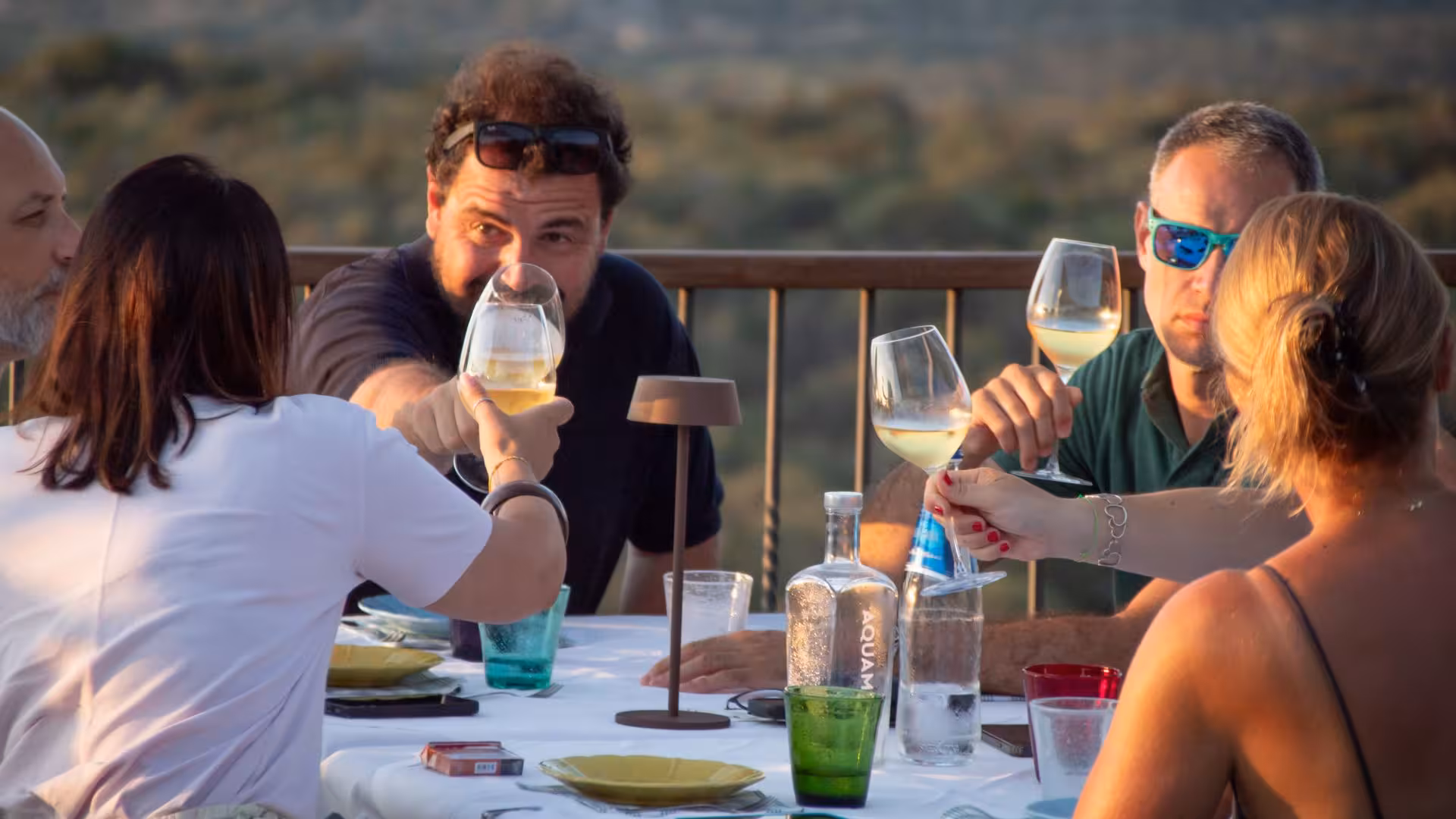 Group enjoying wine tasting in Gallura winery, Palau, with scenic views and vibrant atmosphere.