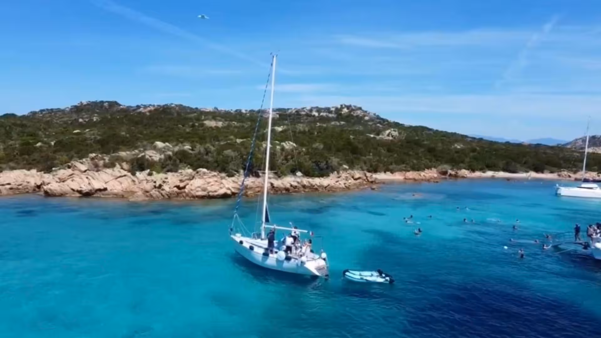 Sailboat anchored in the pristine turquoise waters of La Maddalena, perfect for a Palau sailing excursion.