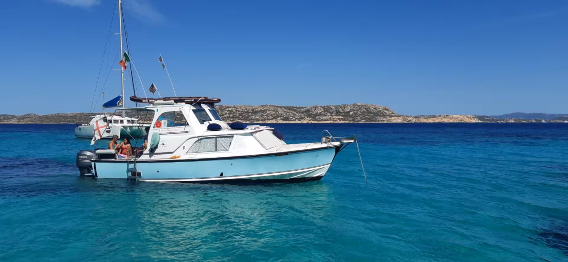 Anchored speedboat in the serene blue waters of La Maddalena Archipelago, perfect for a relaxing Palau tour adventure.
