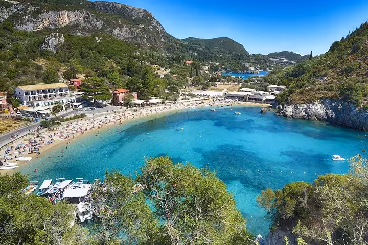 Panoramic view of Paleokastritsa bay with turquoise water and beach crowds on a private Corfu tour