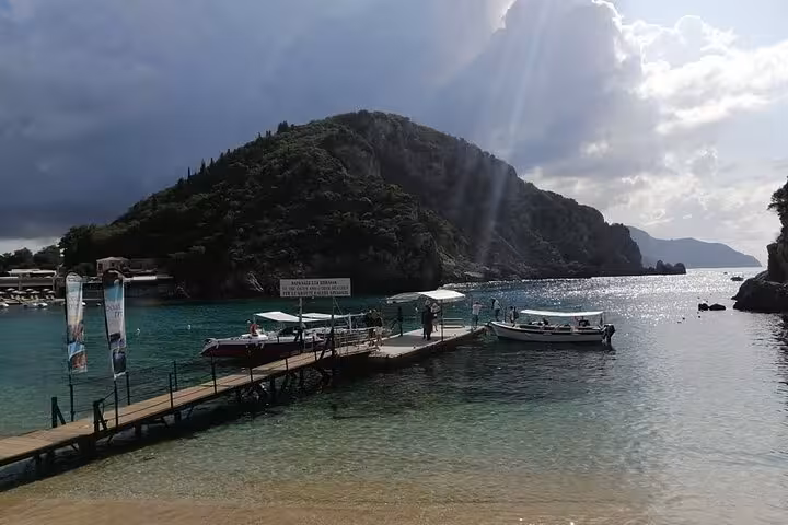 Paleokastritsa harbor pier with boats and sun rays, Corfu private tour stop paired with local food tastings