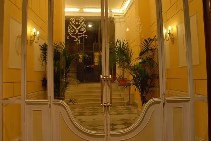 Elegant entrance hall of Hotel del Centro Palermo with glass doors, warm lighting and marble steps for airport transfer guests