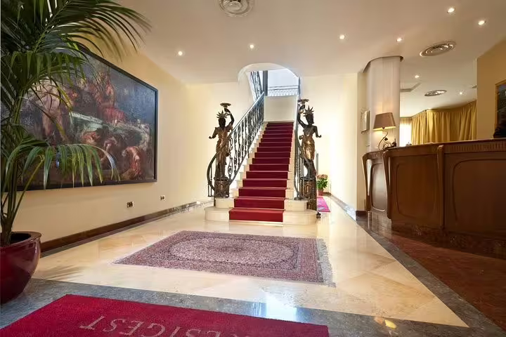 Elegant lobby of Hotel Giardino Inglese in Palermo with red-carpet staircase, ideal arrival point for private airport transfer guests