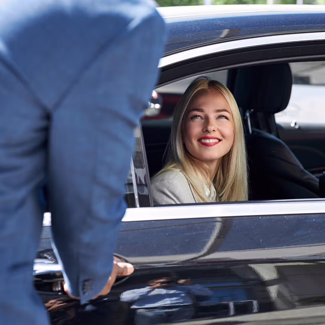 Smiling traveler in back seat of executive car greeted by driver during private Palermo Airport to city transfer service