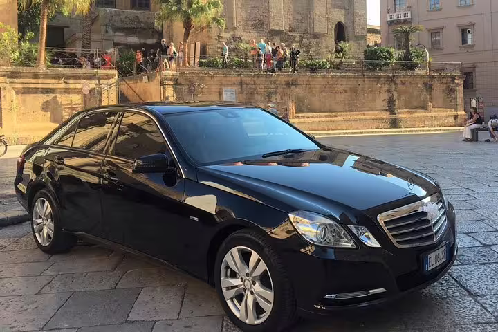 Black executive sedan for private transfer service parked in historic Palermo center, offering comfortable ride from PMO airport to Hotel Politeama