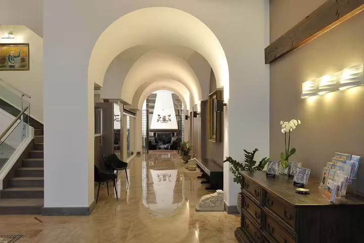 Elegant arched lobby of Hotel Principe di Villafranca in Palermo, welcoming guests arriving by private airport transfer service