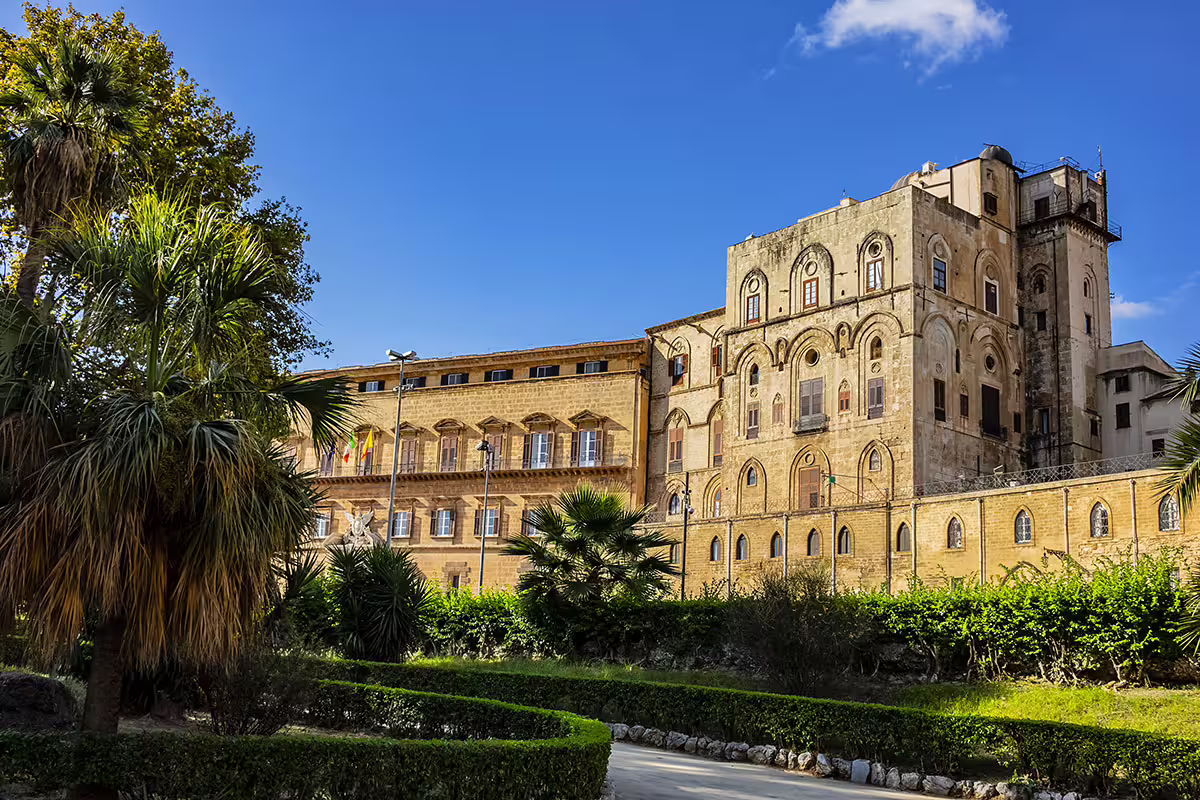 Exterior view of Palermo’s Norman Royal Palace with lush gardens, visited on the Monreale, Palazzina Cinese and Mondello tour