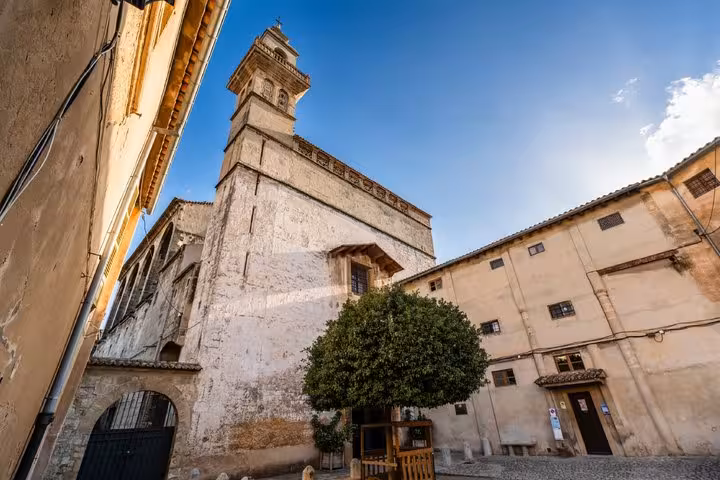 Historic church tower and stone buildings in old town Palma de Mallorca under blue sky