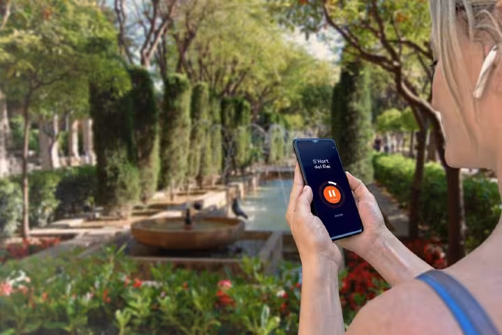 Tourist using audio guide app on smartphone at S'Hort del Rei garden in Palma de Mallorca