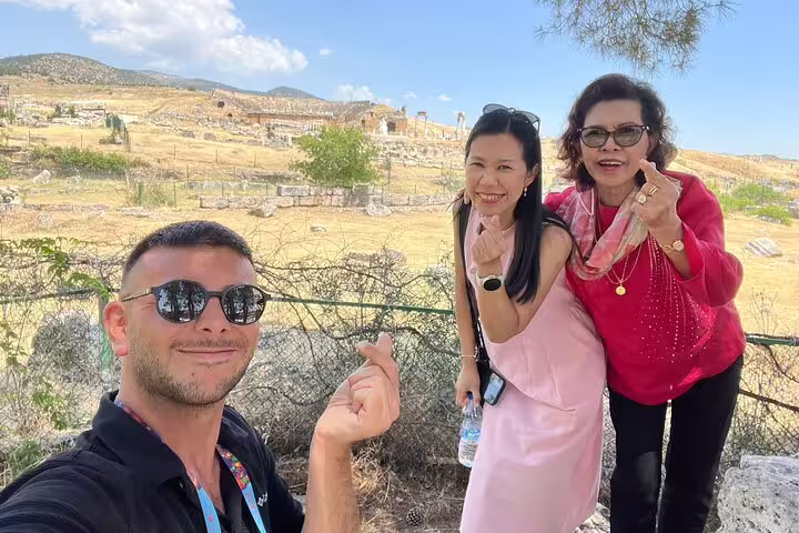 Two women and a man posing happily during a Pamukkale day tour, surrounded by scenic ruins and clear skies.