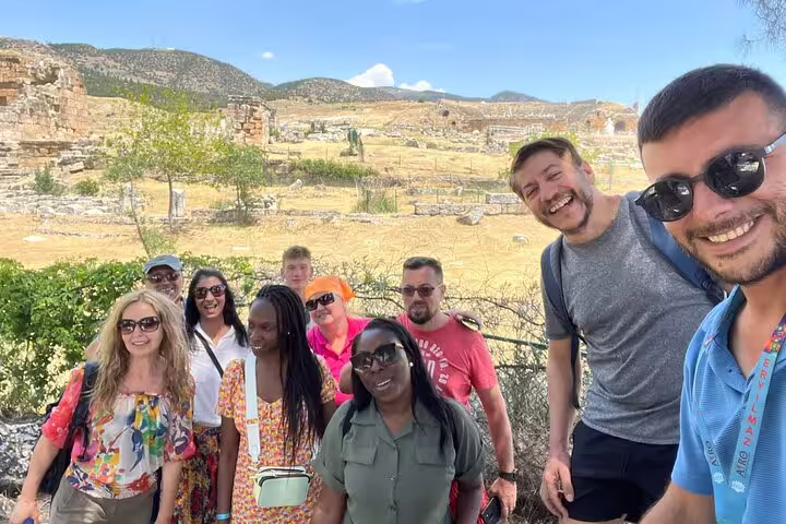 Group of tourists enjoying Pamukkale tour from Istanbul with stunning ancient ruins in the background.