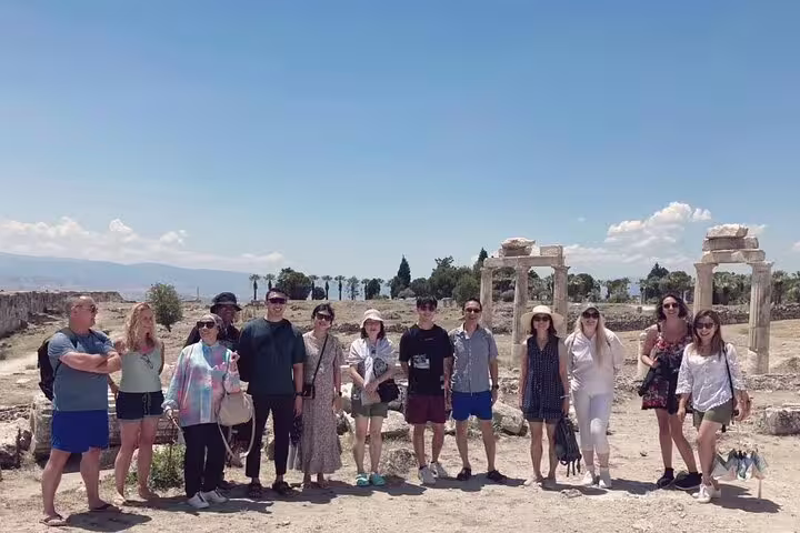 Group of visitors posing by historic stone arches during the Pamukkale excursion from Kusadasi Port.