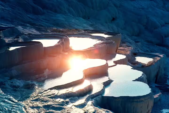 Sunset illuminating Pamukkale's picturesque travertine terraces and pools, showcasing natural beauty on an Istanbul day tour.