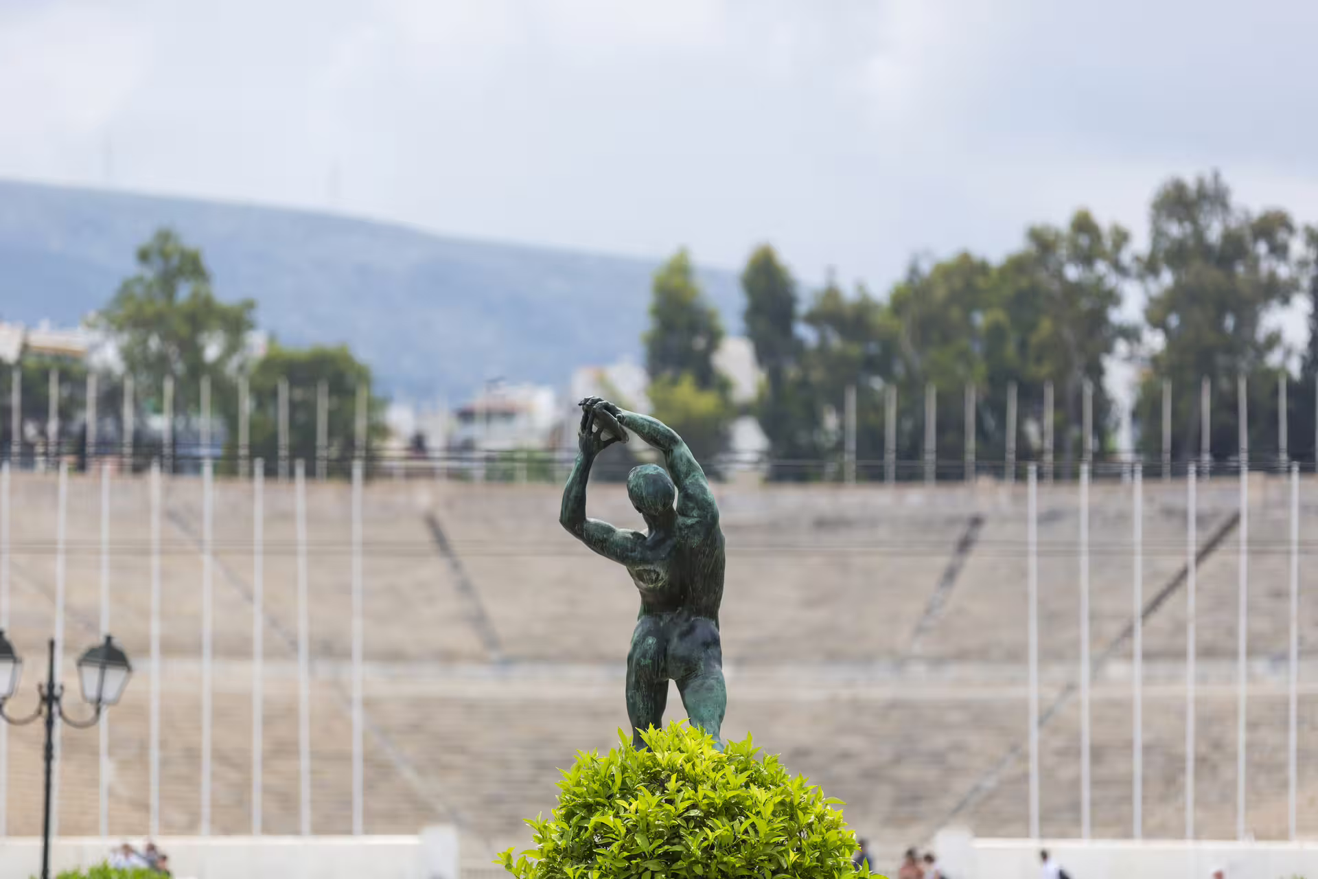Panathenaic Stadium Athens on small group sightseeing tour, bronze athlete statue with marble stands behind