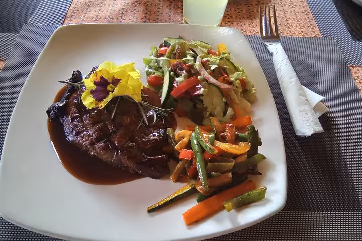 Gourmet steak meal with colorful vegetable sides served during the Panorama Guided Experience culinary tour.