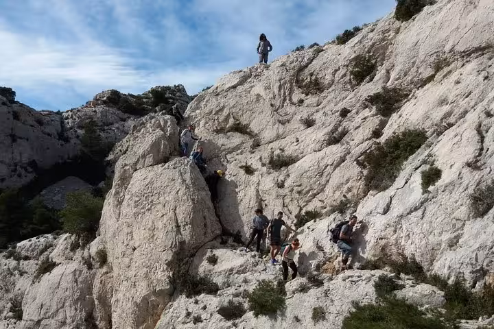 Group trekking across rugged limestone in Les Calanques near Marseille, panoramic guided hike with coastal views