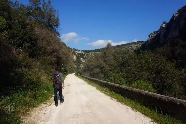 Scenic hiking trail in Pantalica, Sicily, with a traveler exploring breathtaking views on a sunny day tour.