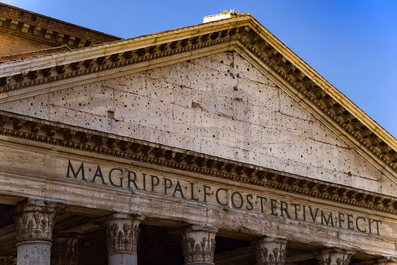 Close-up of the Pantheon's ancient inscription and architectural details against a clear blue sky in Rome.